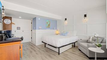 Una camera da letto con un letto, un divano, un tavolino con una pianta, un angolo cottura e un armadietto in legno.
