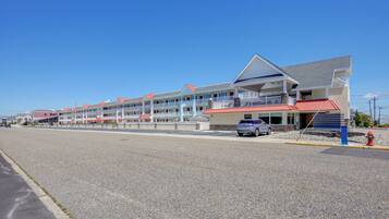A motel with multiple balconies, a parking lot, and a fire hydrant.