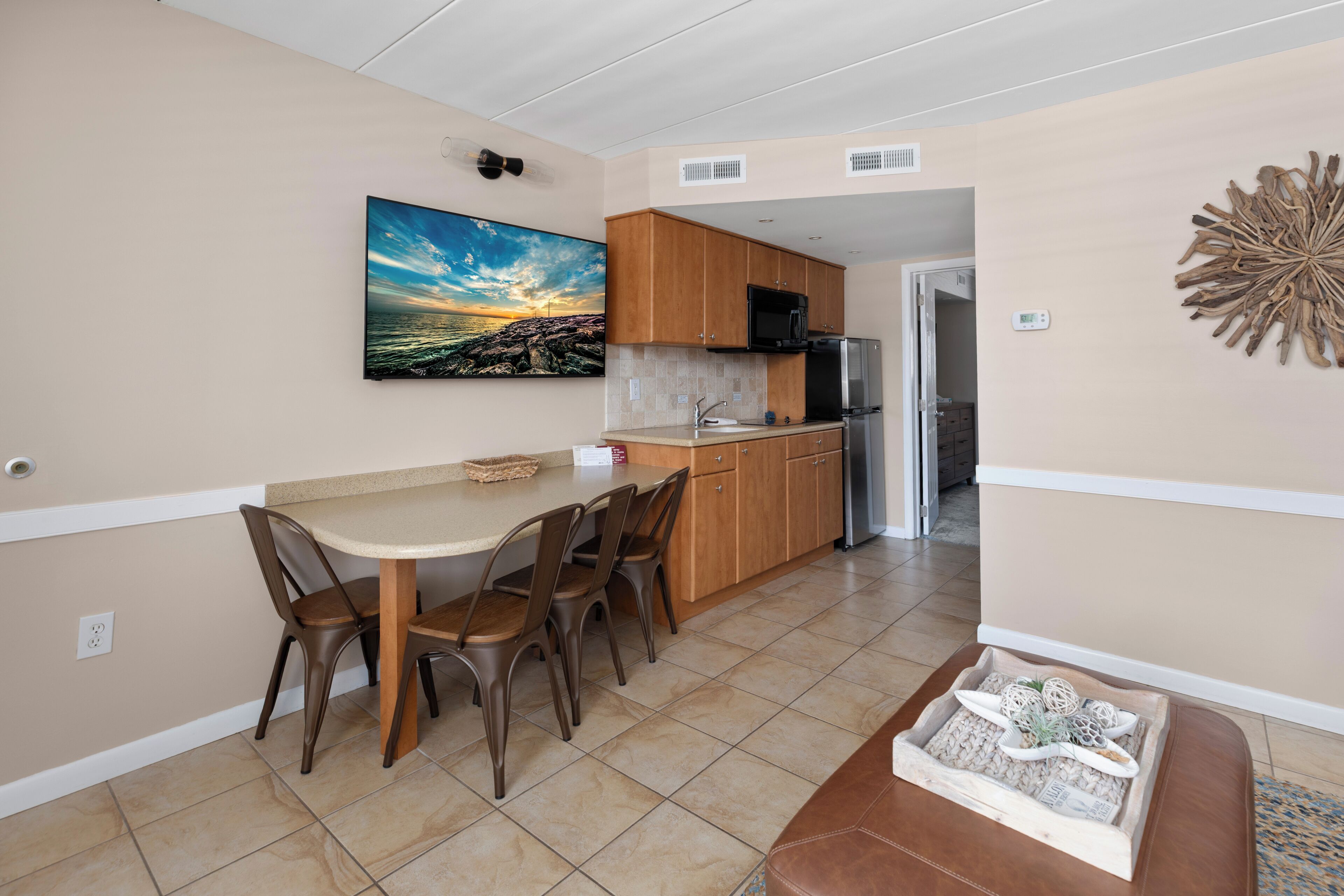 A kitchen with wooden cabinets, a stainless steel refrigerator, and a dining area with a table and chairs.