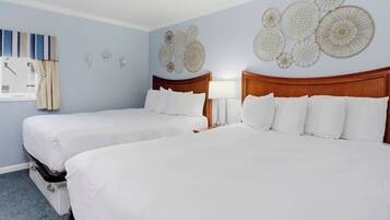 A hotel room with two beds, a window with curtains, and wall decor.