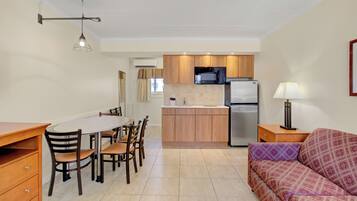 A compact kitchen with a dining area, a sofa, and a lamp.