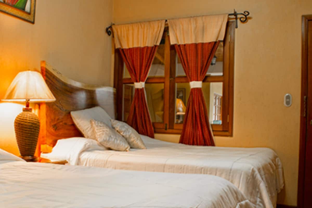 Une chambre d’hôtel avec deux lits, une lampe et des rideaux.