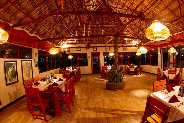 An indoor dining area with wooden flooring, red chairs, and tables set for dining. - Hotel Dos Mundos (Panajachel)