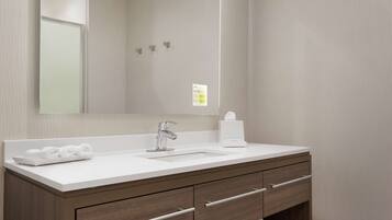 A modern bathroom with a white sink, a mirror, and wooden cabinetry.
