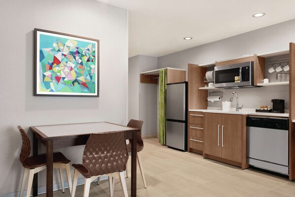 Una cocina moderna con comedor, que incluye refrigerador, microondas y armarios.