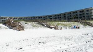 Un hotel fronte spiaggia con numerosi balconi, passerelle in legno e una zona di spiaggia sabbiosa.