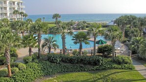 Un resort con piscina, palme e vista sull'oceano.