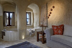 A room with a bathtub, a sofa, a small table, and a wall-mounted light fixture.