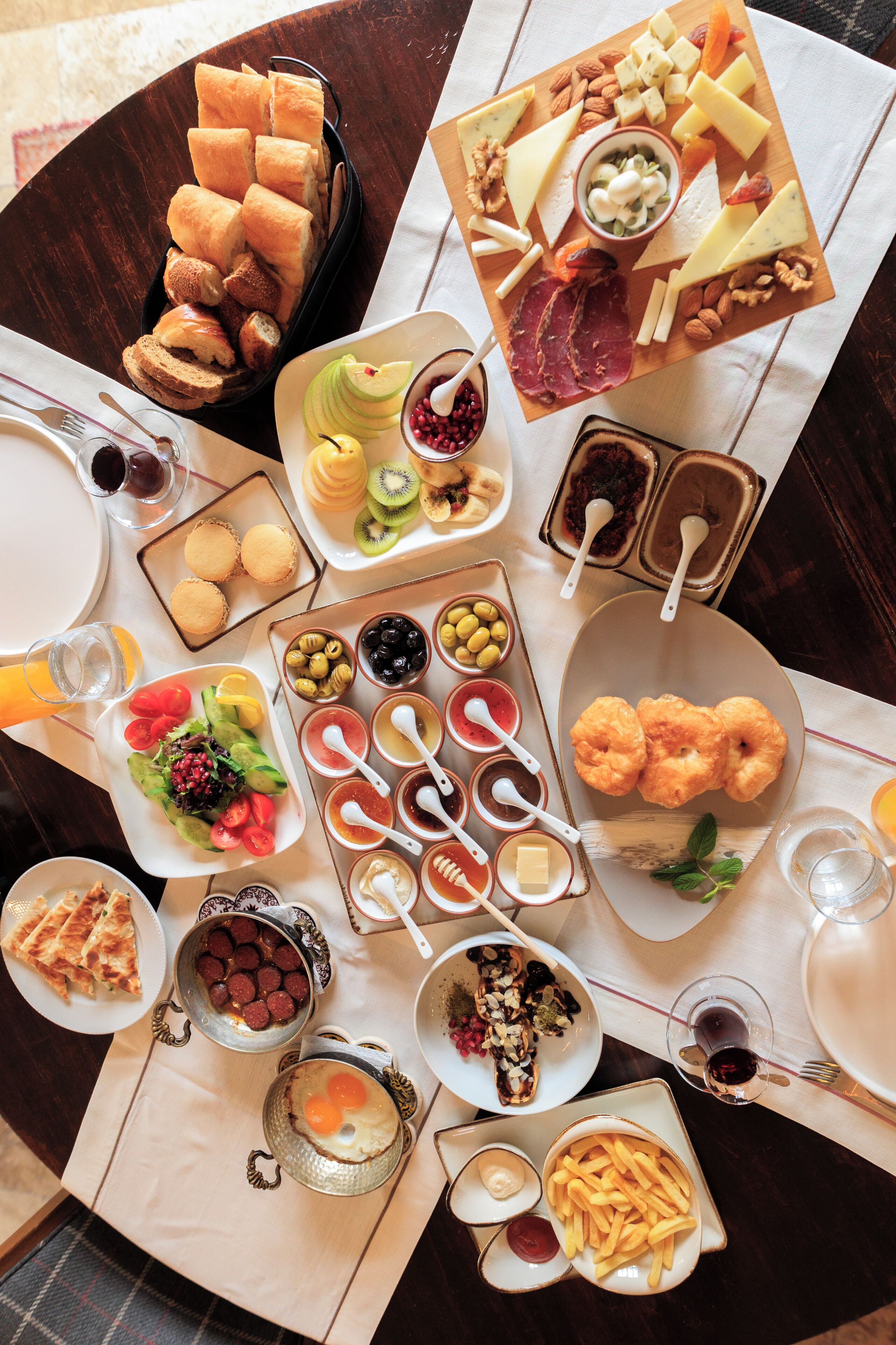 A table with various food items and condiments, including cheese, fruits, and bread.