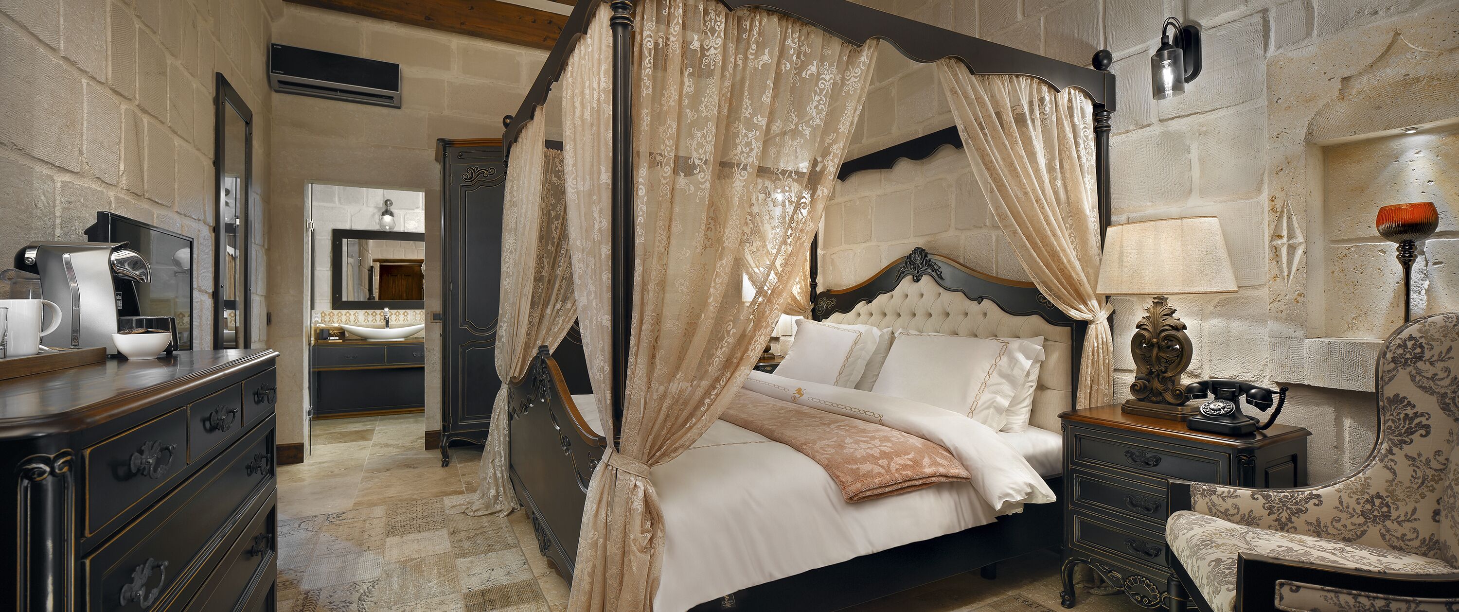 A four-poster bed with a canopy, a bedside table with a lamp, and a chair.