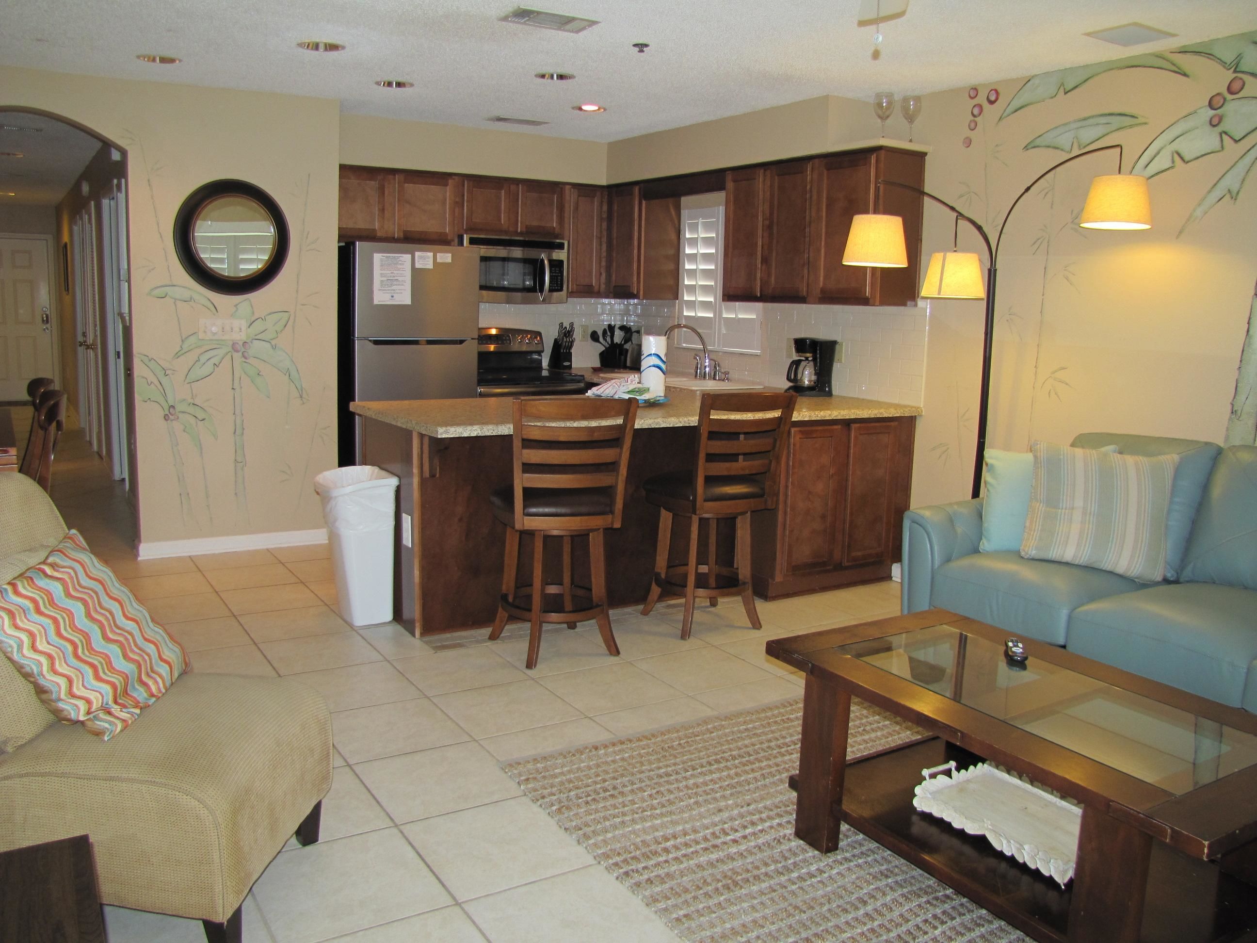 A compact living space with a kitchenette, a sofa, a coffee table, and a dining area with two chairs.