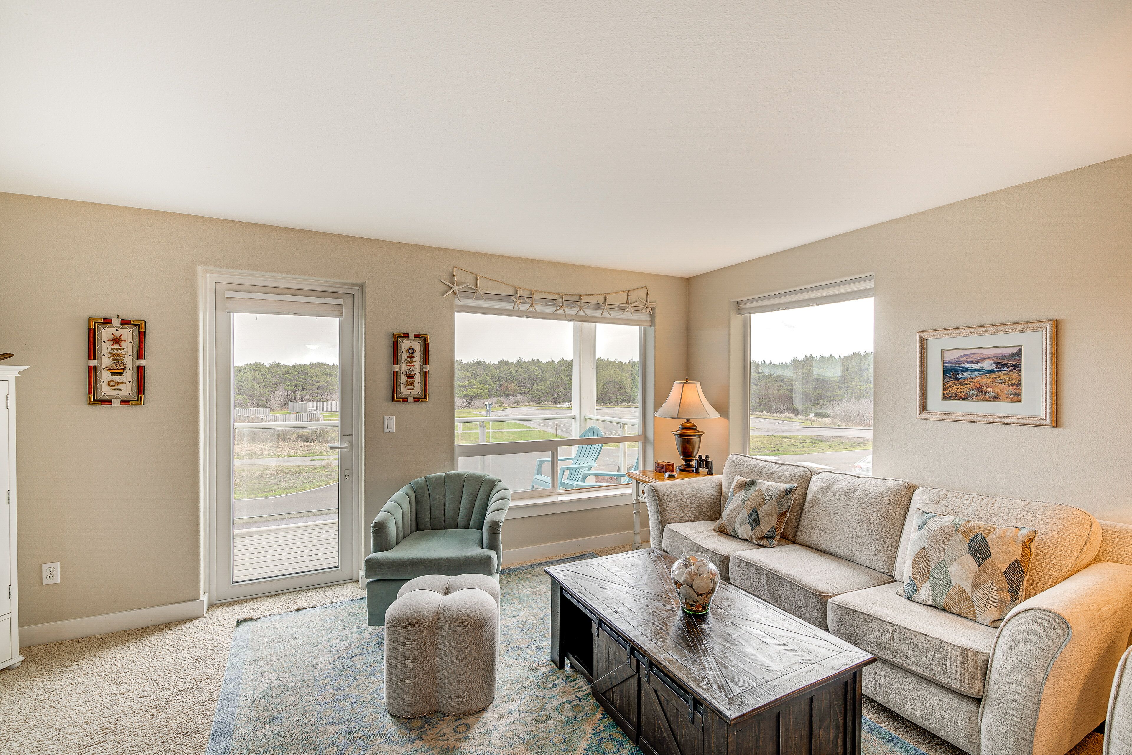 A spacious living room with a large window, a sofa, a chair, and a coffee table.