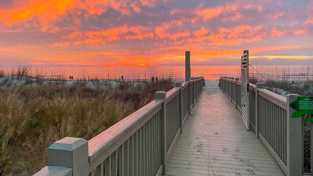 A wooden boardwalk leading to a beach with a sunset in the background. - Lagoon & Fountain Views: Villa in Palmetto Dunes (Hilton Head)