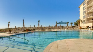 A clear blue pool with sun loungers and palm trees, surrounded by a building with balconies. - Lagoon & Fountain Views: Villa in Palmetto Dunes (Hilton Head)