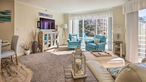 A living room with a TV, two blue armchairs, a sofa, and a wooden coffee table. - Lagoon & Fountain Views: Villa in Palmetto Dunes (Hilton Head)