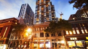 A high-rise building with multiple floors, large windows, and a construction crane in the background. - Penthouse Apartment in Melb CBD Perfect Location (Melbourne)