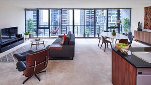 A modern living room with a sofa, coffee table, and dining area. - Penthouse Apartment in Melb CBD Perfect Location (Melbourne)
