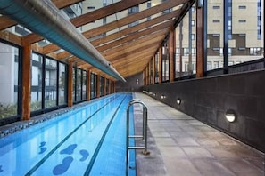 Swimmers can enjoy a refreshing dip in the pool surrounded by glass walls offering views of the outside.