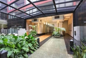 Enter a contemporary space with a high ceiling, polished tiles, and lush greenery.