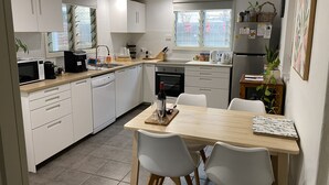 A modern kitchen with white cabinets, a wooden countertop, and a dining area with two white chairs.
