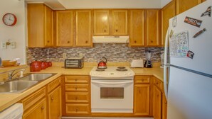 A kitchen with wooden cabinets, a white stove, and a refrigerator. - Walk to Ocean: Myrtle Beach Condo w/ Screened Deck (Myrtle Beach)
