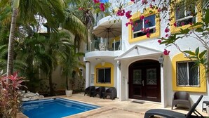 A two-story building with a swimming pool, outdoor seating, and tropical plants. - LOVELY VILLA IN PLAYACAR PHASE 1,  PRIVATE POOL (playa del carmen)
