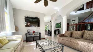 A spacious living room with a glass coffee table, a sofa, and a TV mounted on the wall. - LOVELY VILLA IN PLAYACAR PHASE 1,  PRIVATE POOL (playa del carmen)