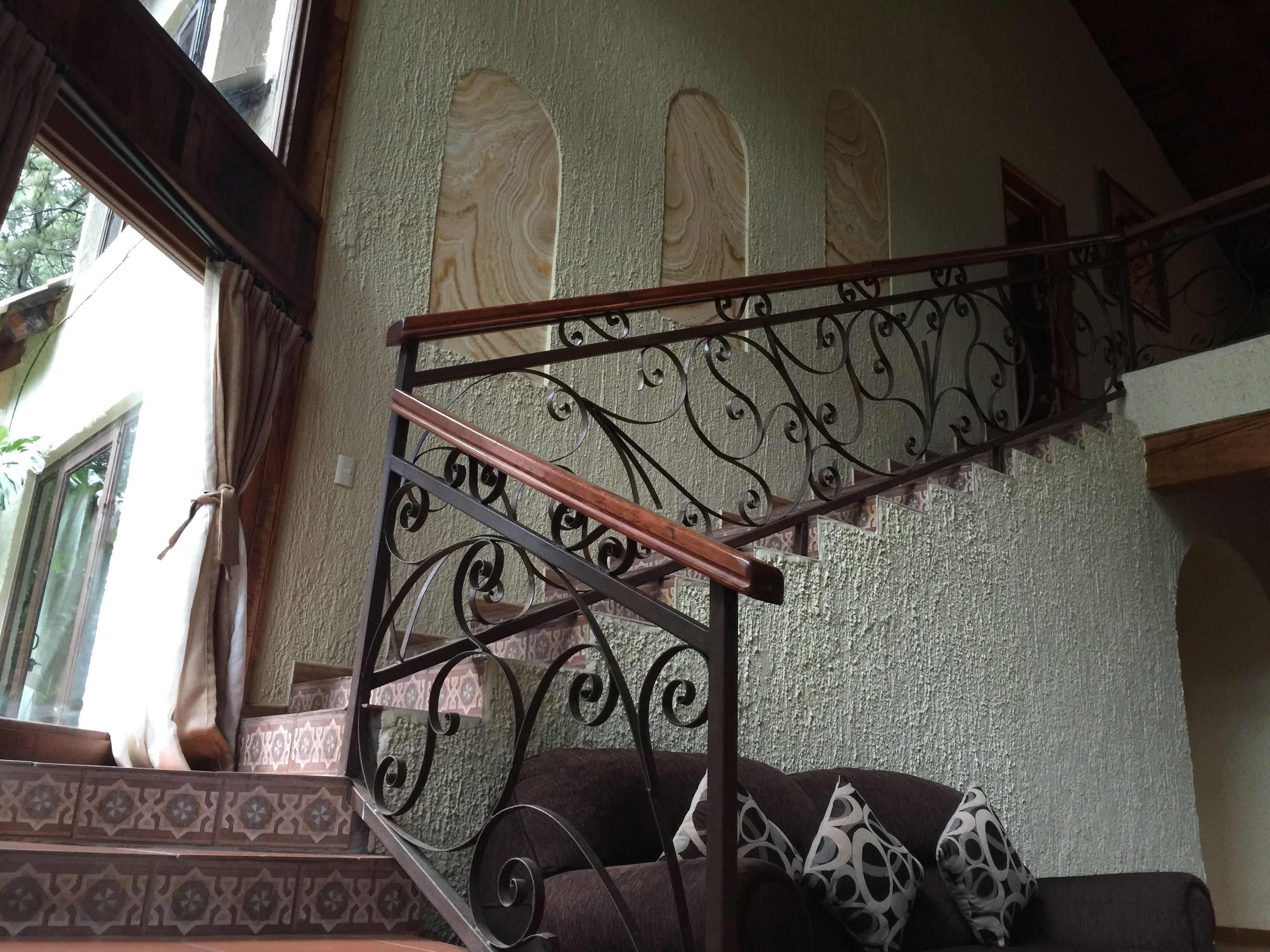 Una escalera con barandillas de metal ornamentadas y un revestimiento de pared con diseño.