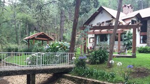 En hyggelig lodge med en bro af sten, omgivet af frodig vegetation og en velholdt have.