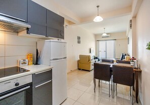A compact kitchen with modern appliances, a dining area with a table and chairs, and a separate seating area with a sofa.