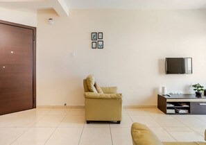 A living room with a sofa, a chair, a TV, and a cabinet. - LightHouse by the Sea Lovely 2Bdr Apartment (Paphos)