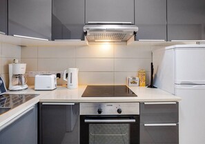 A modern kitchen with a built-in oven, a coffee maker, a toaster, and a refrigerator. - LightHouse by the Sea Lovely 2Bdr Apartment (Paphos)