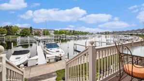 A marina with boats docked, a wooden deck, and a railing. - Remodeled Harbor Condo Steps to Lake MI (Manistee)