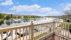 A marina with boats docked, a clear sky, and a residential area in the background. - Remodeled Harbor Condo Steps to Lake MI (Manistee)