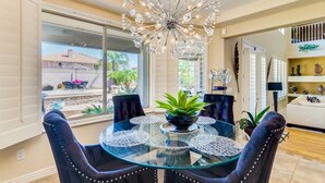 A dining area with a glass table, dark upholstered chairs, and a decorative chandelier.