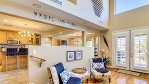 A spacious living area with two wicker chairs, a dining area with a bar, and a kitchen with modern appliances. -  LUXURY DREAM HOME, 6 bdrm, gameroom, firepits, pool, hot tub, 5000 sq ft (Peoria)
