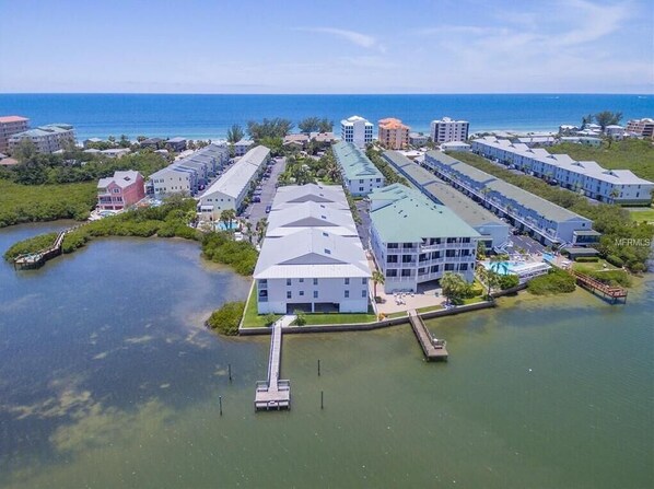 An aerial view of a coastal hotel with multiple buildings, a dock, and a marina.