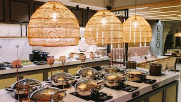 A buffet setup with multiple food stations and overhead wicker chandeliers.