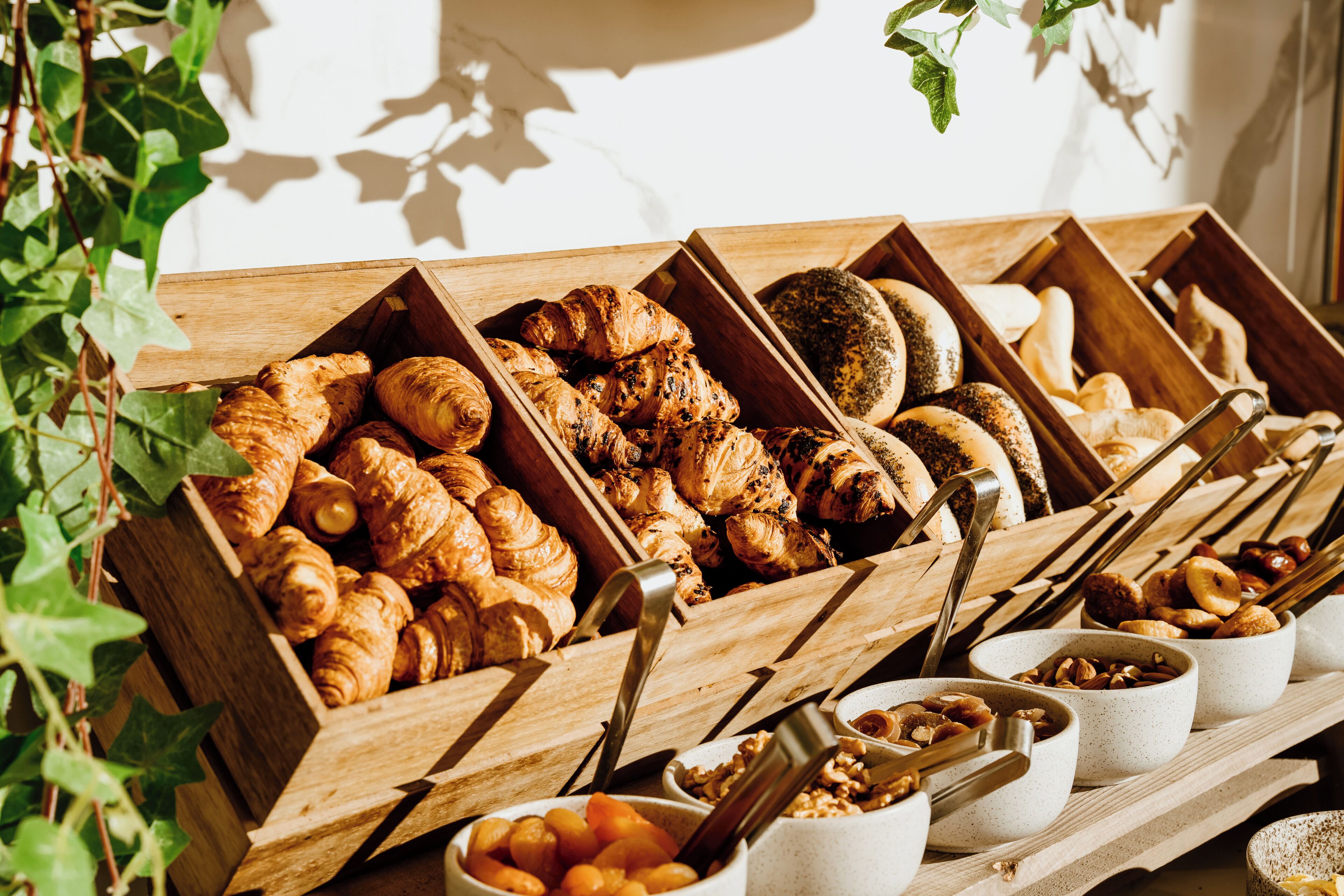 A variety of baked goods displayed in wooden boxes and bowls, including croissants and pastries.