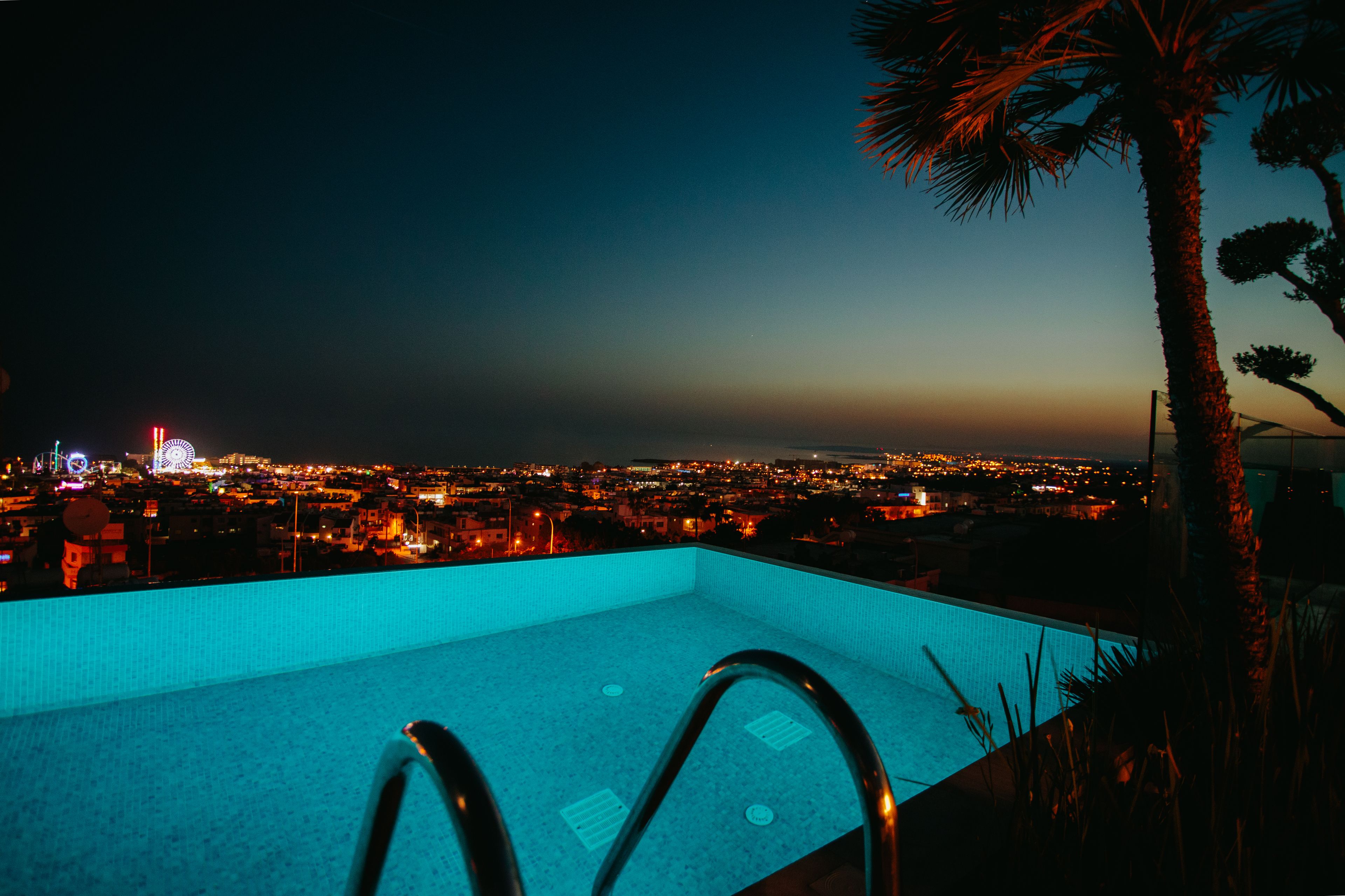 A pool with a view of a cityscape at dusk.
