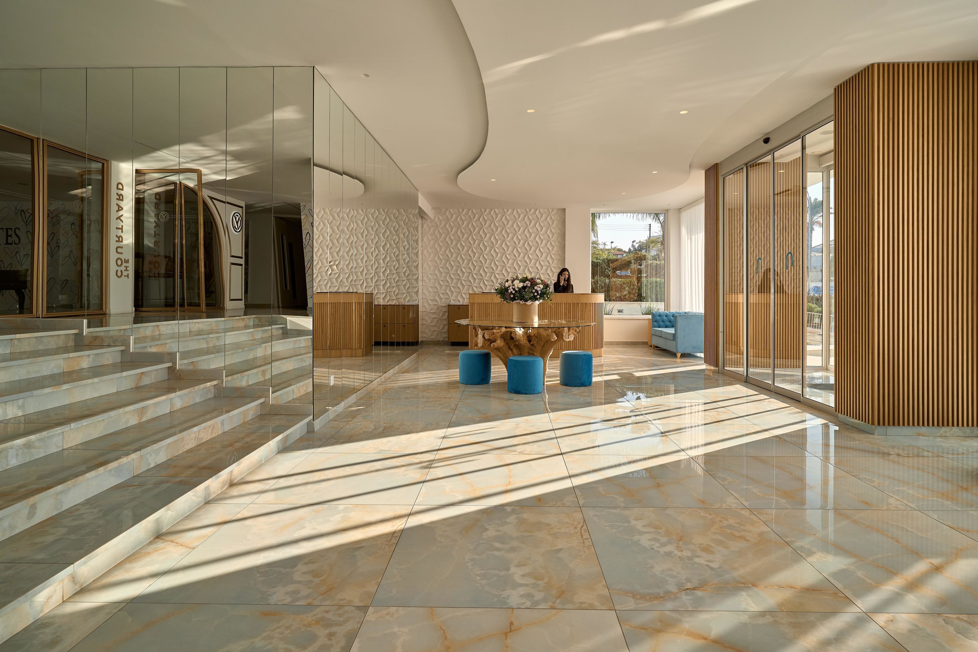 Eine moderne Lobby mit Marmorboden, Glaswänden und einer Rezeption.
