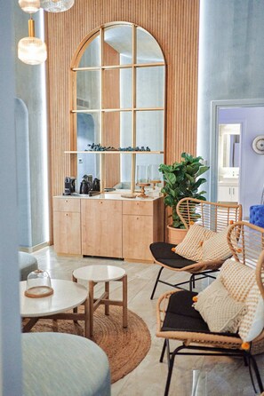 A modern kitchen with wooden cabinets, a large mirror, a coffee machine, and a potted plant.