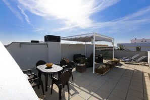 A rooftop patio with a table and chairs, a covered seating area, and potted plants. - ATIC - Only Families (Cambrils)