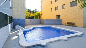 Ein Schwimmbecken mit geometrischen Fliesen an der Umrandung, einer Sitzbank und einer Springbrunnen.