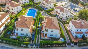 An aerial view of a residential area with multiple houses, a central swimming pool, and well-maintained gardens. - MASIA2 adosado jardín privado, BBQ y piscina comun (Miami Playa)