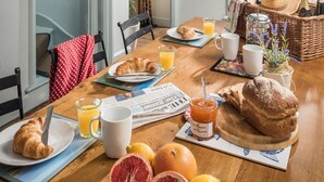 A breakfast table with croissants, orange juice, and grapefruit.
