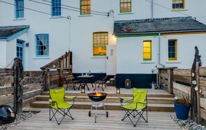 Una terraza de madera con mobiliario exterior y un brasero.