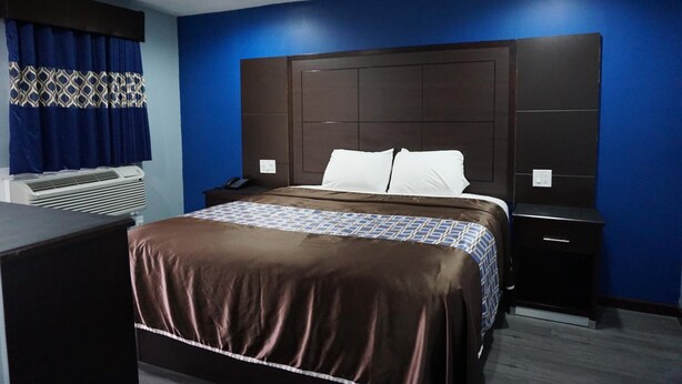 A hotel room with a large bed, a nightstand, a desk, and a ceiling fan. - Star Light Inn (Channelview)