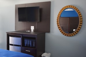 A hotel room with a flat-screen TV mounted on a dark wall, a microwave, and a small trash bin. - Star Light Inn (Channelview)