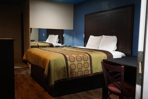 A hotel room with two beds, a desk, and a chair.